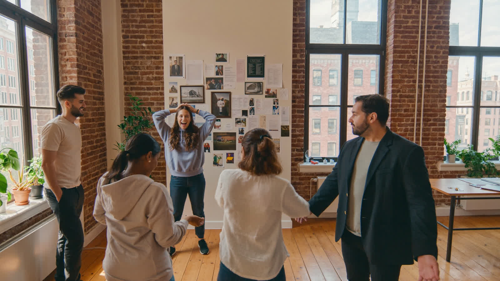 A founding team laughing together by a wall of plans in a brick loft