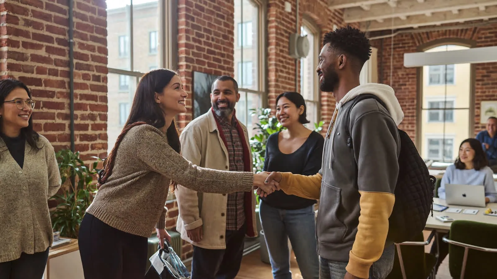 Founders greeting each other in a brick loft with tall windows
